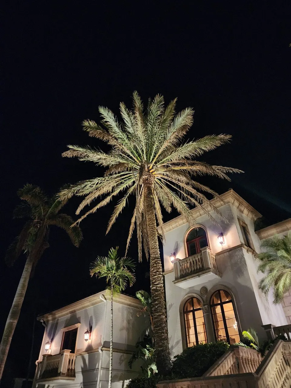 The upper floor and balcony of a house at night with wall lanterns lit
