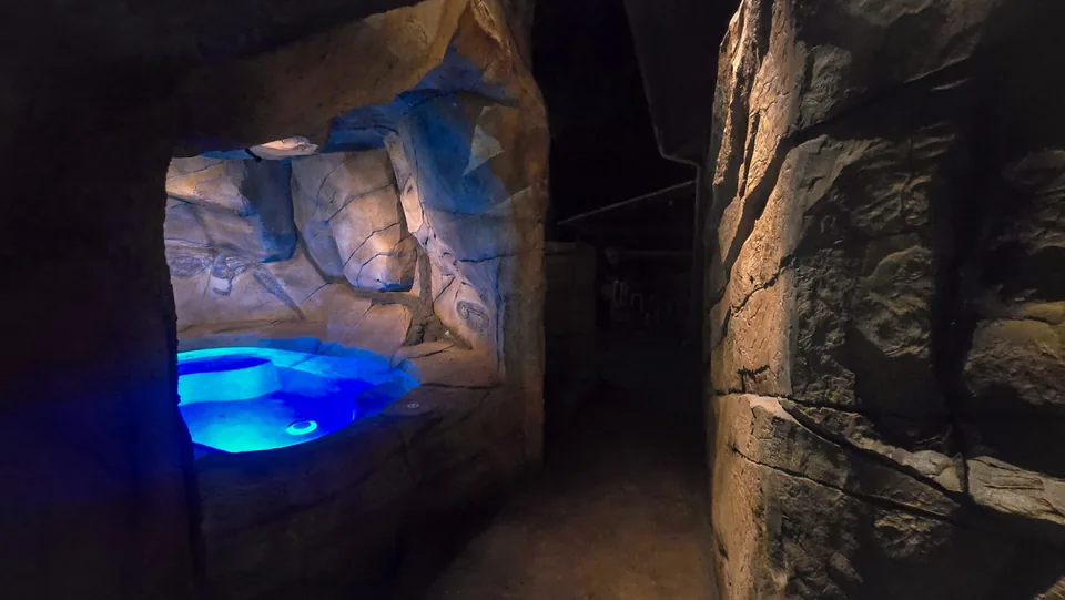 A rock grotto with a spa lit blue from under the water, the light itself a bright point on the bottom
