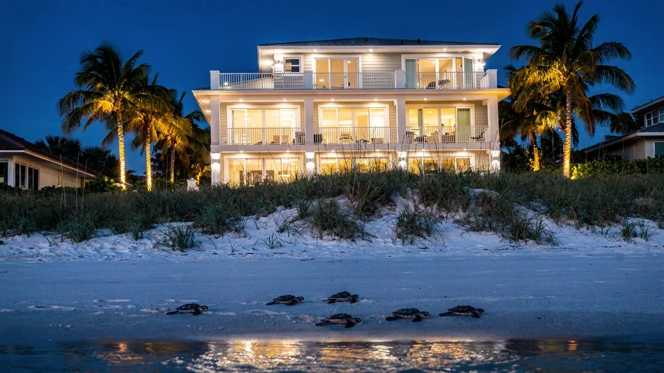 Illustration of the same beach house with every light on, seen from the sand