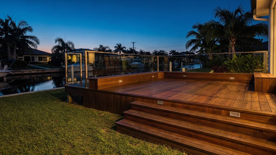 A raised timber deck with wide steps behind a canal-front house at dusk