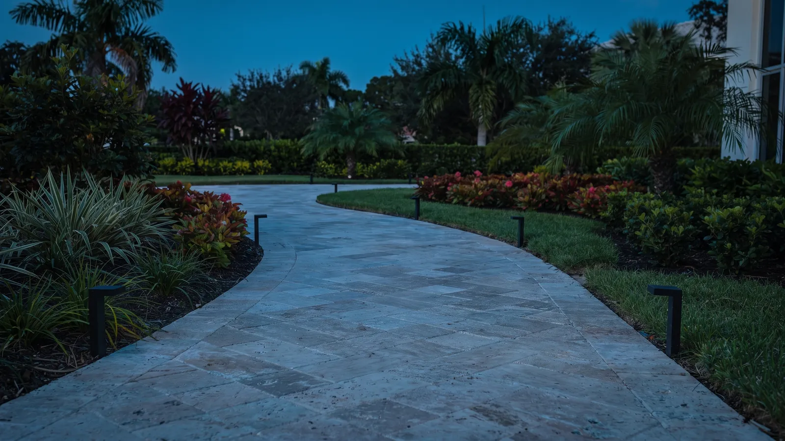 A stone path curving through planting at dusk with low fixtures along its edge